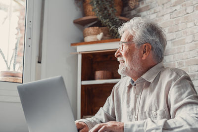 Side view of man using digital tablet while standing at home
