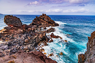 Scenic view of rocks in sea against sky