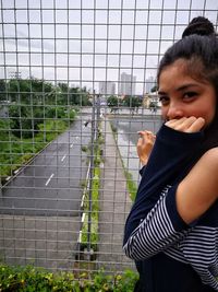 Portrait of woman standing by fence