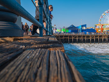 People on pier at beach against sky