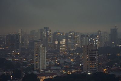 Illuminated buildings in city against sky at night