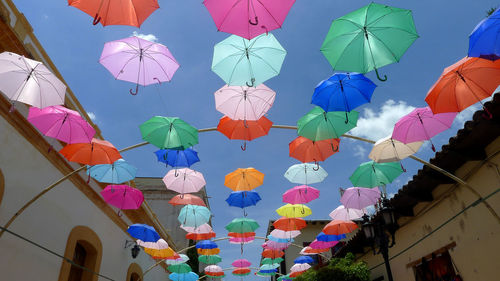 Low angle view of multi colored umbrellas hanging against blue sky