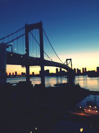 Suspension bridge over river at dusk