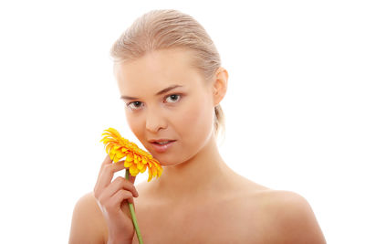 Portrait of young woman holding flower against white background