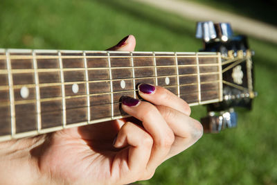 Cropped hand of woman playing guitar at public park