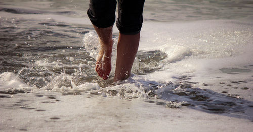 Low section of woman running in sea