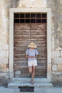 Full length rear view of woman standing against brick wall