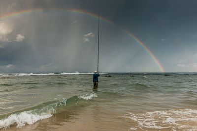 Rear view of man standing in sea against sky