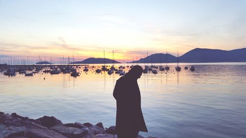 Man standing by sea during sunset