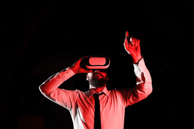 Rear view of man with arms raised standing against black background