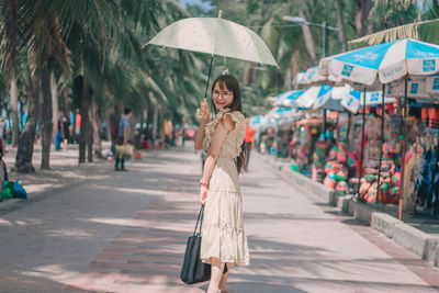 Portrait of beautiful woman wearing eyeglasses standing on footpath