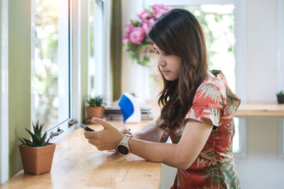 Woman using smart phone sitting at cafe