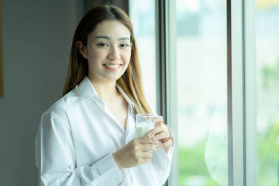 Portrait of young woman using mobile phone at home