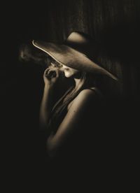 Close-up of young woman over black background
