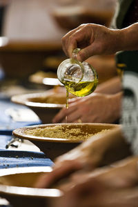 Cropped image of woman pouring oil in bowl