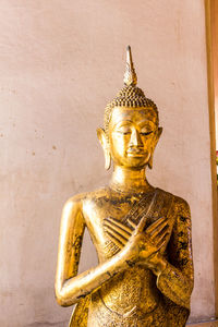Statue of buddha against wall of building