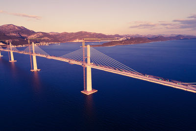 Suspension bridge over sea against sky