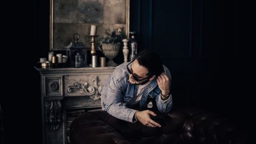 Young man wearing sunglasses sitting in darkroom