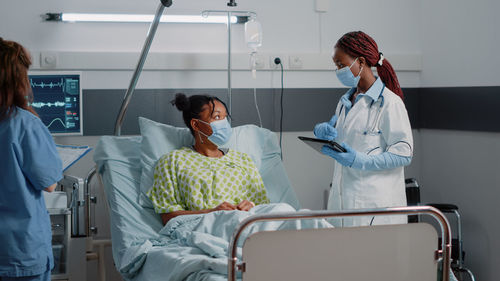 Doctor with nurse examining patient in ward at hospital