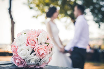 Close-up of rose bouquet with couple in background