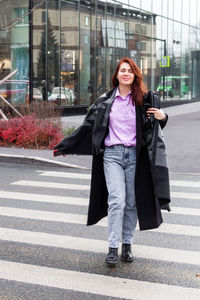 Lifestyle portrait of beautiful smiling business woman in casual clothing is walking in a city. 