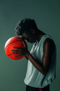 Man holding ball while standing against gray background