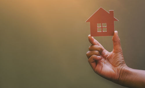 Close-up of hand holding small house in building