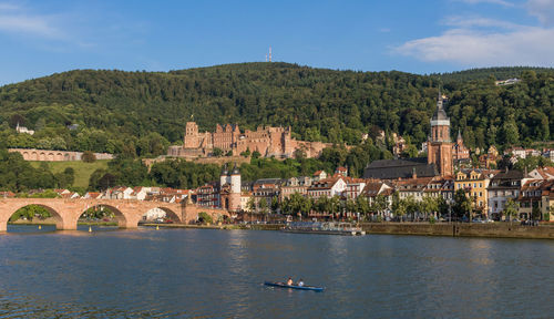 Scenic view of river by buildings against sky