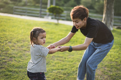 Side view of mother and daughter walking on field