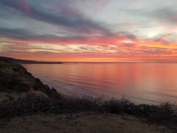 Scenic view of sea against dramatic sky during sunset