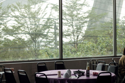 Empty chairs and table against trees seen through window