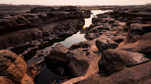 Rock formations by sea against sky