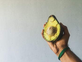 High angle view of hand holding fruit against wall