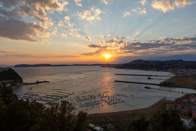 High angle view of sea and buildings against sky during sunset