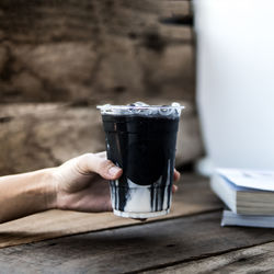 Close-up of hand holding drink on table