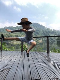 Boy jumping at observation point against mountain
