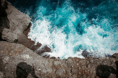 High angle view of sea waves splashing on rocks