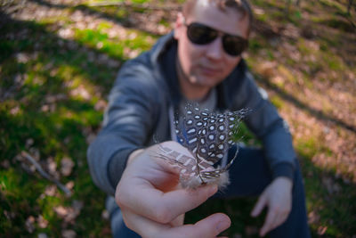 Midsection of man holding sunglasses against plants