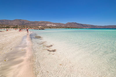 Scenic view of beach against clear blue sky