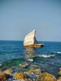 Scenic view of rock formation in sea against clear sky