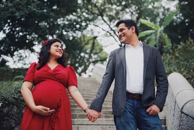 Pregnant couple holding hands while standing on steps