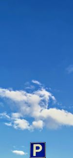 Low angle view of sign against blue sky