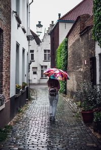 Rear view of woman walking on wet street during monsoon