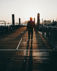 Morning, rear view of man walking on footpath against sky