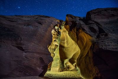 Low angle view of rocky mountains against star field at night