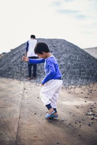 Side view of boy playing with stone on street