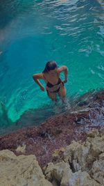 Rear view of shirtless man swimming in sea