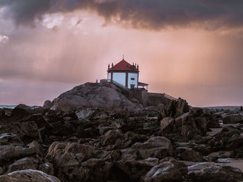 Chapel on rock by sea against sky