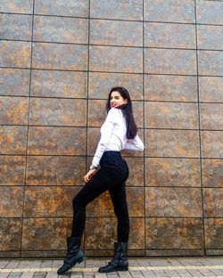 Side view portrait of young woman standing against wall