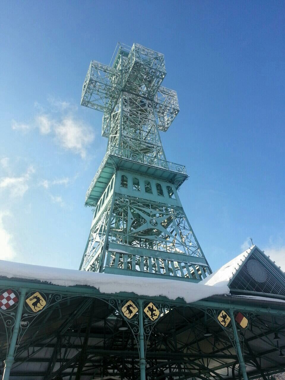 low angle view, built structure, architecture, communication, text, building exterior, sky, western script, tower, tall - high, blue, day, clear sky, city, outdoors, no people, information, tall, metal, famous place